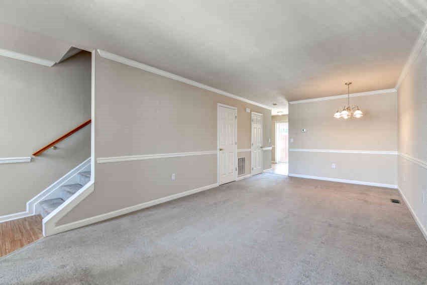 an empty living room with white walls and a staircase