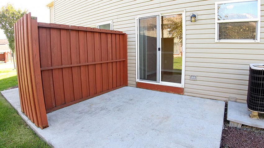 a backyard patio with a wooden privacy fence