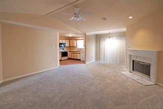 an empty living room with a fireplace and a kitchen