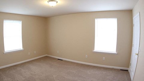 a living room with two windows and a carpet