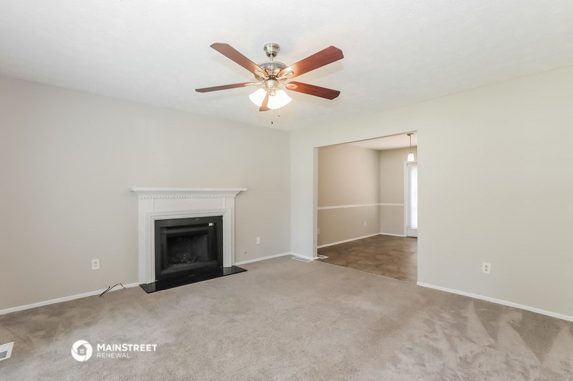 the living room with fireplace and ceiling fan