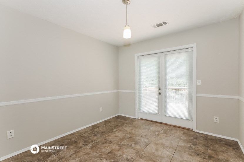 the spacious living room with large windows and tile flooring