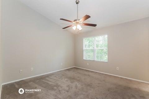 the spacious living room with carpet and ceiling fan