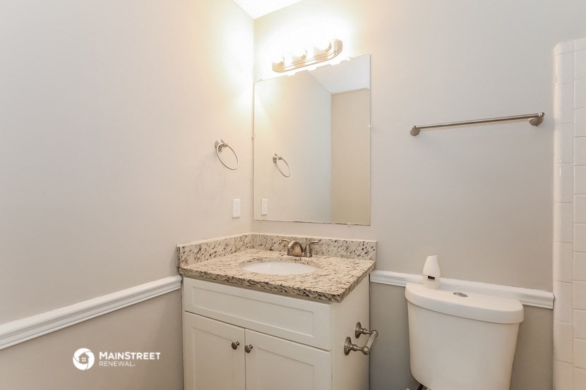 a white bathroom with a white toilet and a sink and a mirror