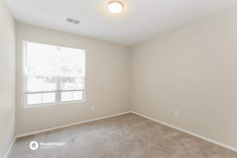an empty room with a large window and carpet