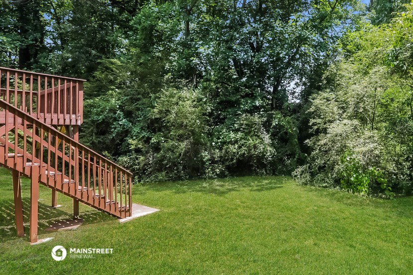 a backyard with a deck and grass and trees