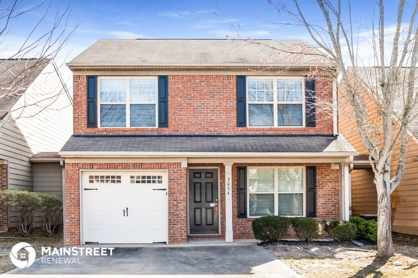 a home with a white garage door and a red brick house