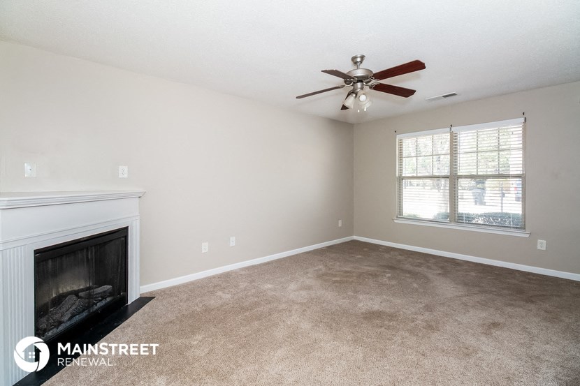 a living room with a fireplace and a ceiling fan