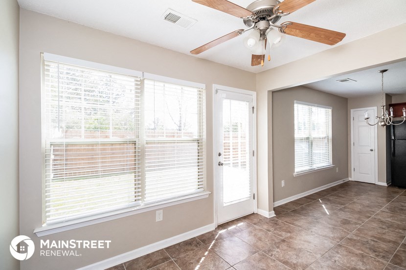 a living room with large windows and a ceiling fan
