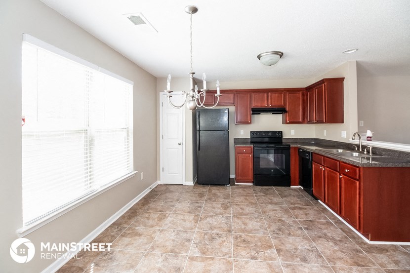 a kitchen with wood cabinets and black appliances and a large window