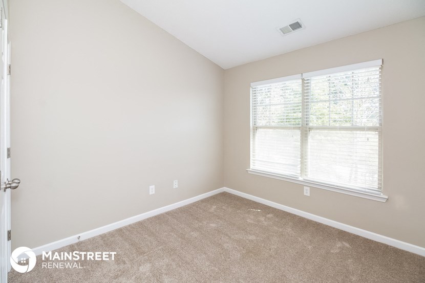 a bedroom with a carpeted floor and a large window