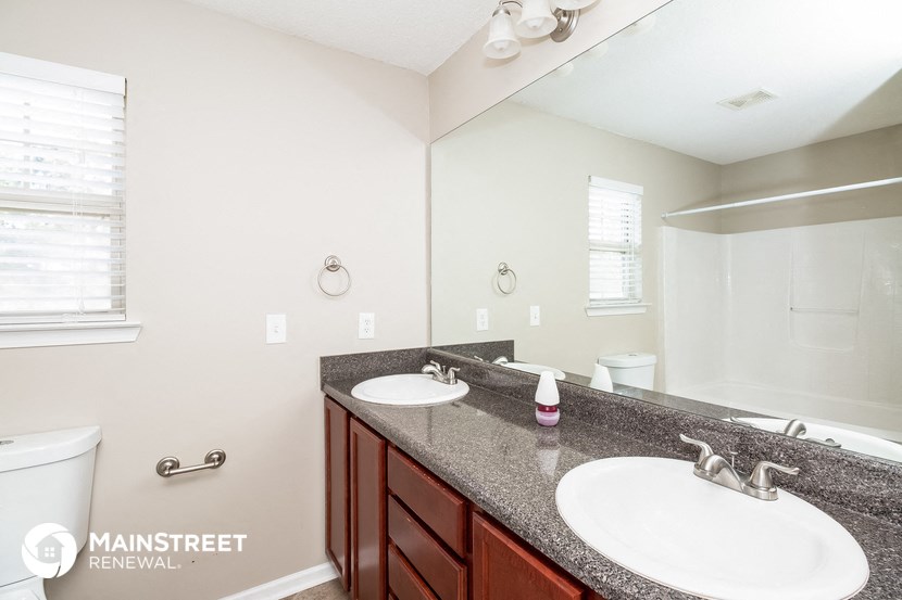 the master bathroom has dual sinks and a large mirror