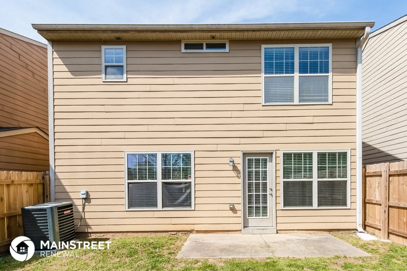 the exterior of a home with tan siding and a wooden fence