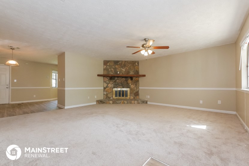 an empty living room with a fireplace and a ceiling fan