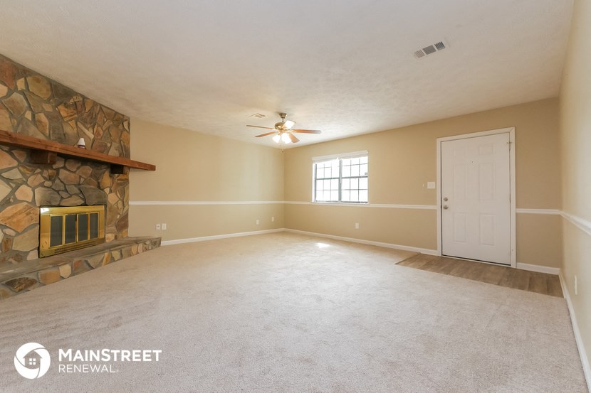 an empty living room with a fireplace and a ceiling fan