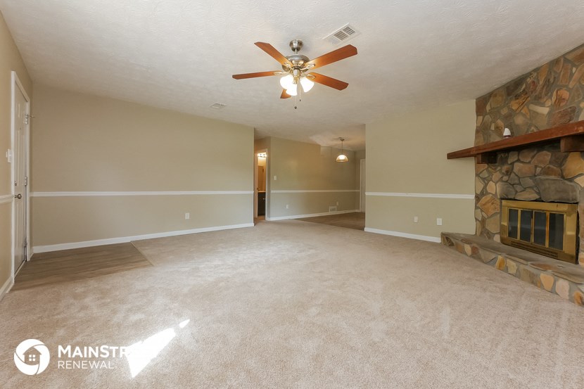 an empty living room with a fireplace and a ceiling fan