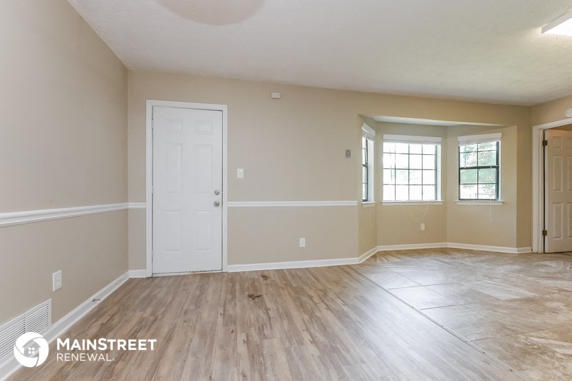 the spacious living room with wood flooring and a white door