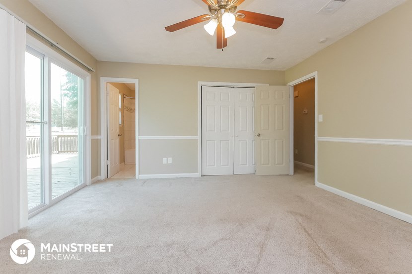 an empty living room with a ceiling fan and a door to a balcony