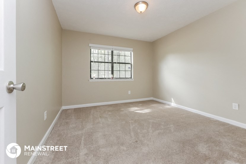 the spacious living room with carpeting and a window