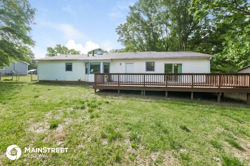 a white mobile home with a deck and a grassy yard