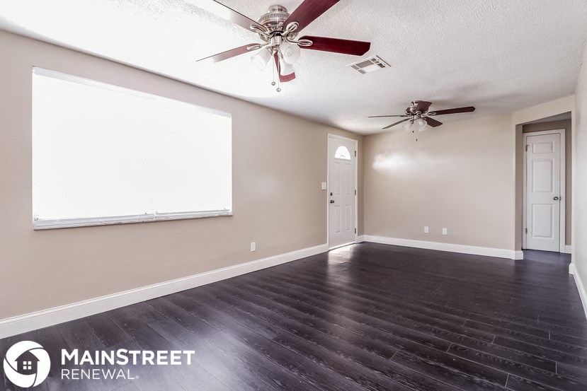 an empty living room with a projector screen and a ceiling fan