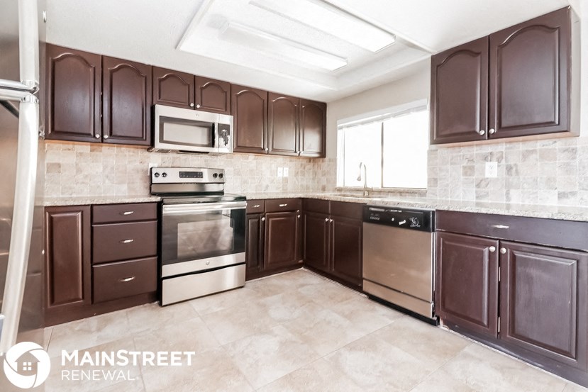 a kitchen with dark wood cabinets and stainless steel appliances