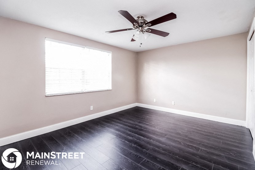 an empty living room with wood floors and a ceiling fan