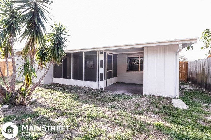 a small white house with a palm tree in the yard
