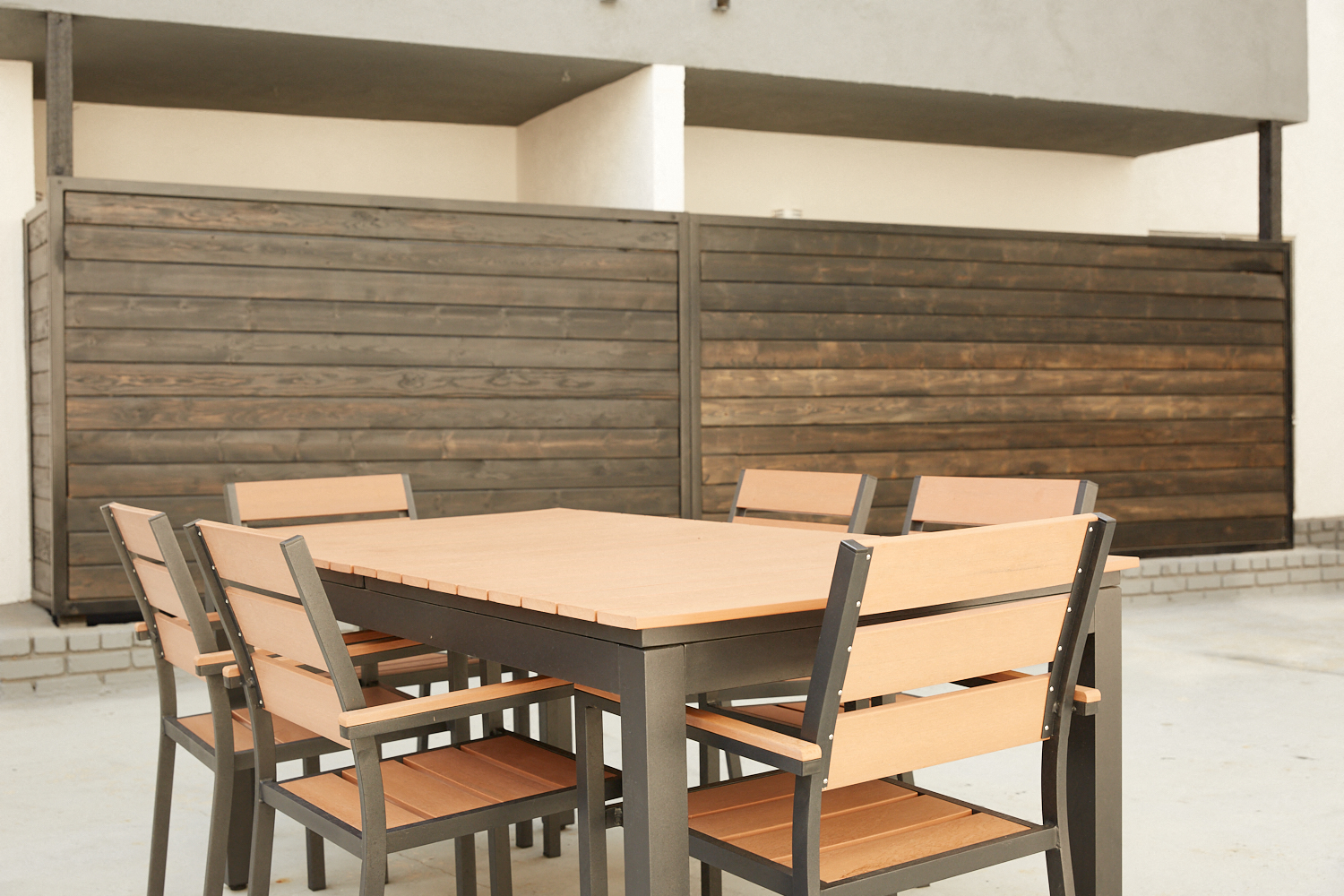 a dining table and chairs in front of a wooden wall