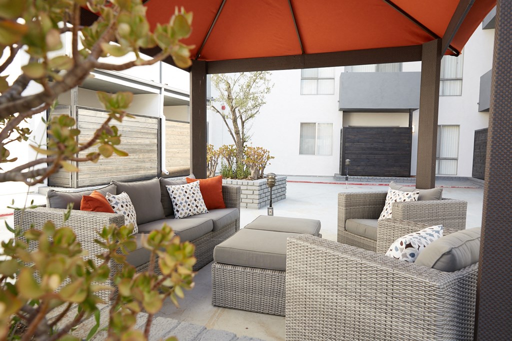 a patio with couches and chairs under an orange umbrella
