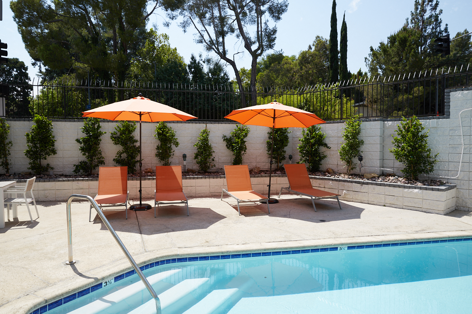 a pool with orange umbrellas and chairs next to a pool