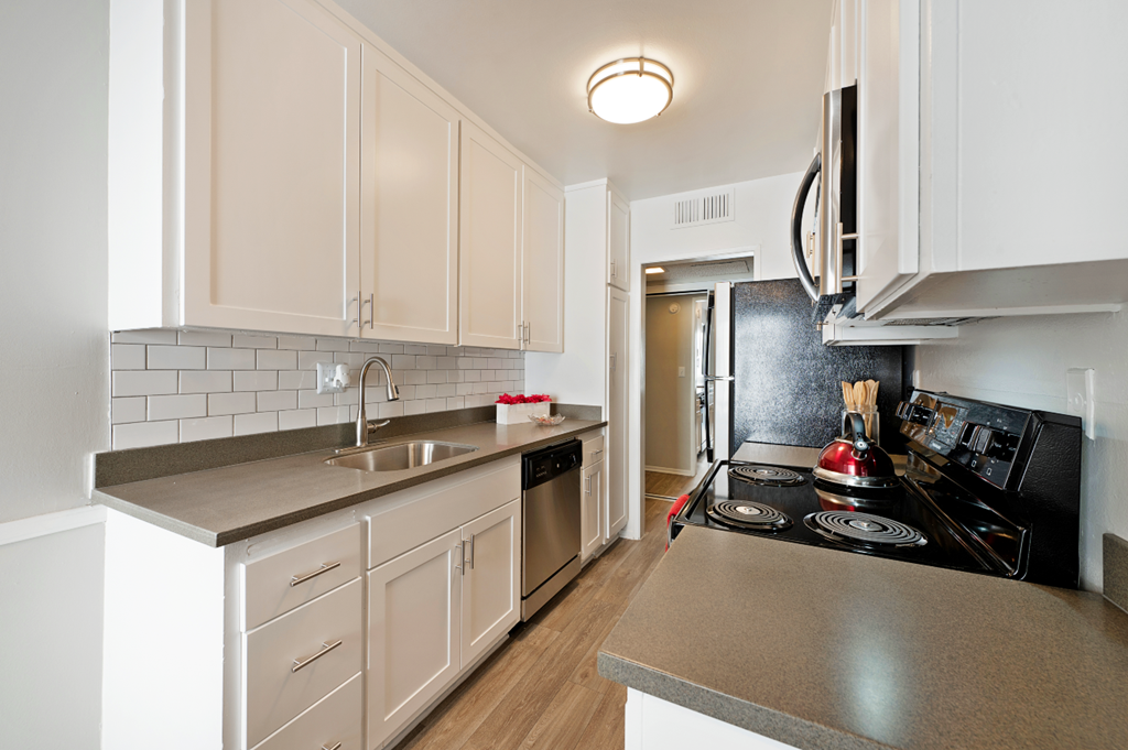 a kitchen with white cabinets and black appliances and a sink