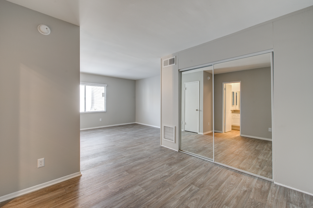 an empty living room with mirrors and a wooden floor