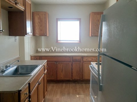 A kitchen with wooden cabinets and a stainless steel refrigerator.
