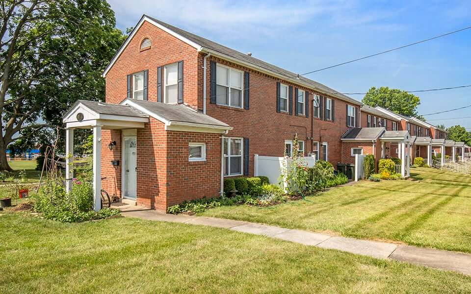a red brick house with a lawn and a sidewalk
