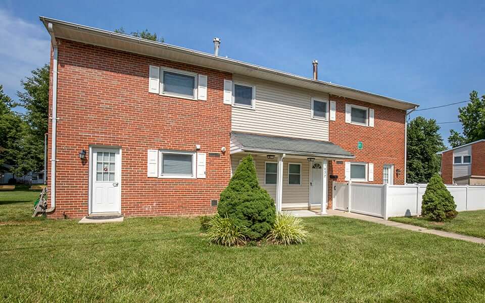 a brick house with a white fence and a lawn
