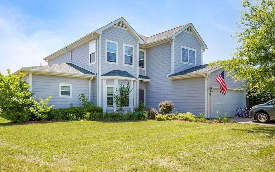 a blue house with an flag on the lawn