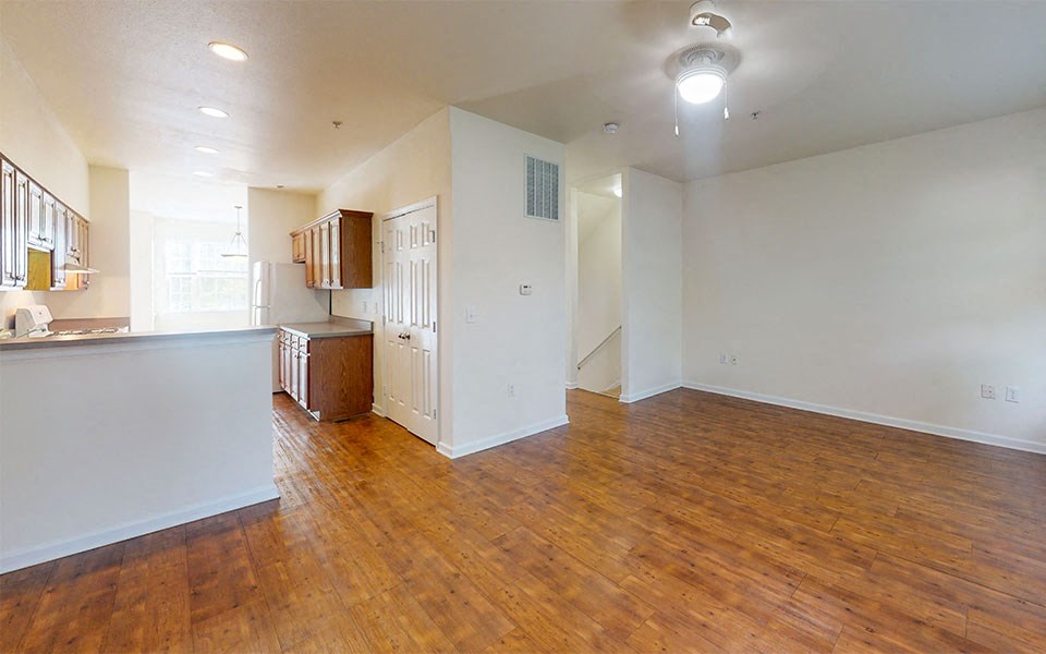 an empty living room and kitchen with wood floors