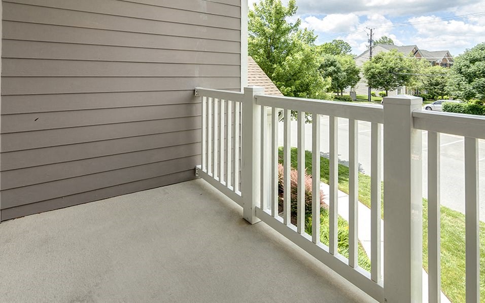 a balcony with a white railing and a yard with a house