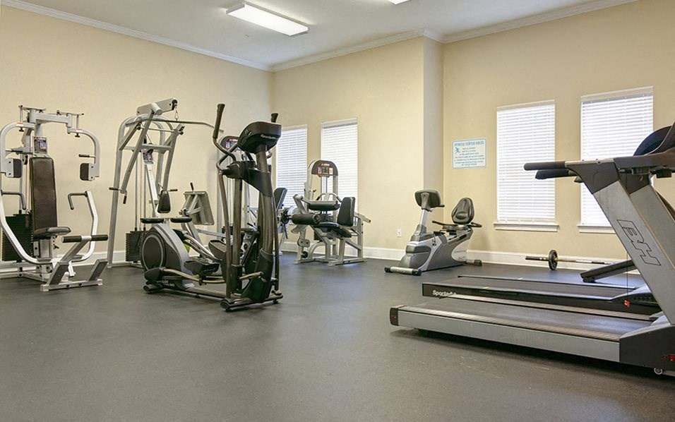 a gym with cardio equipment and weights on the floor