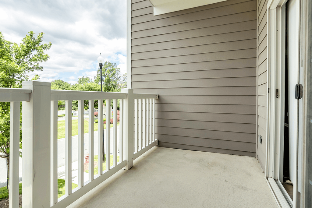 the porch of a home with a white railing and a door