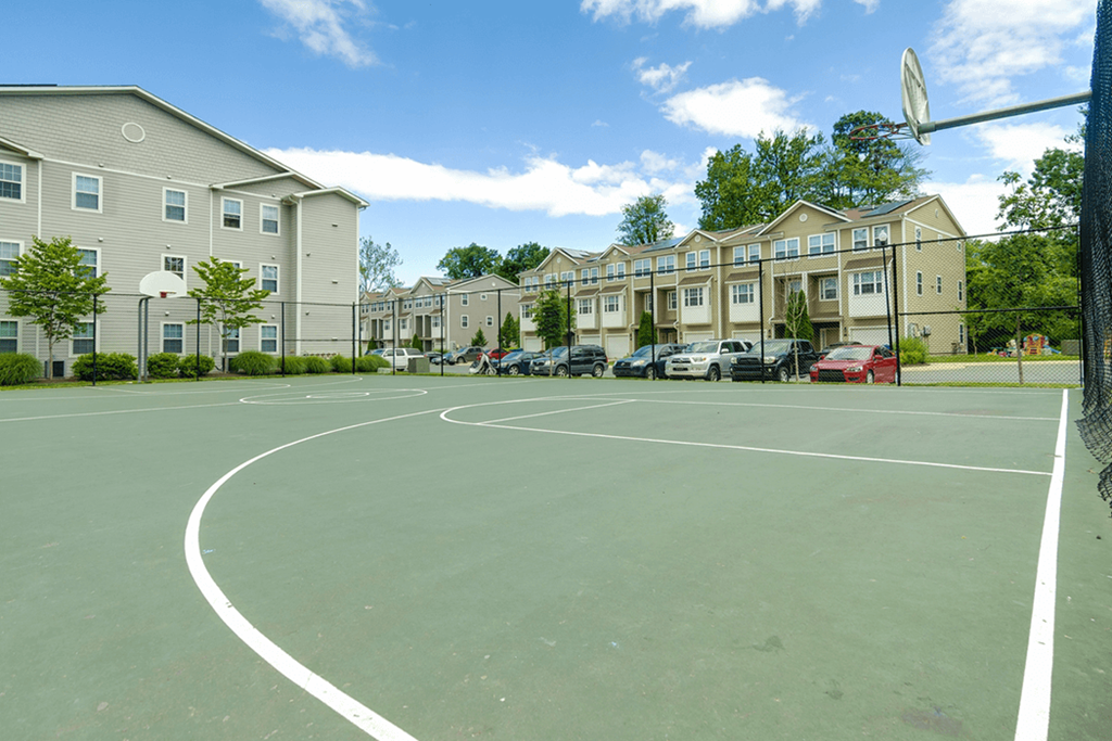 a basketball court in front of a row of apartment buildings