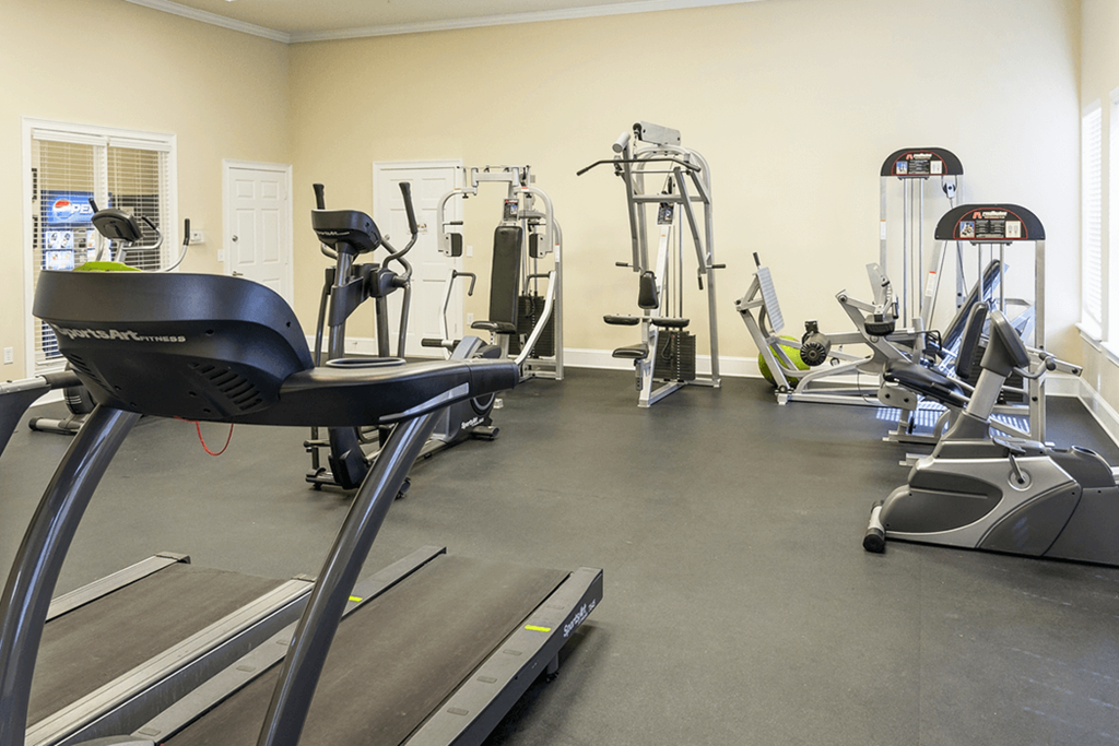 a gym with cardio equipment and weights on the floor