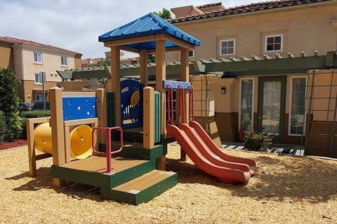 a playground with a playset and slides in front of a building