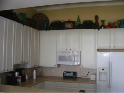 A kitchen with white cabinets and a white refrigerator.