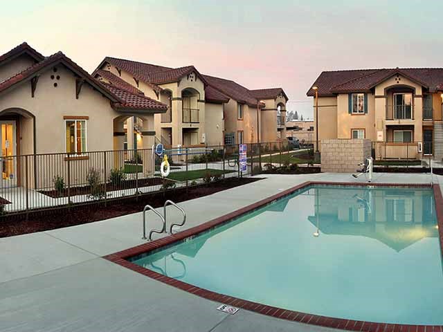 Pool view by buildings l Cordova Apartments in Selma CA