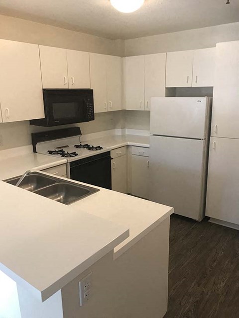 a white kitchen with a sink and a refrigerator