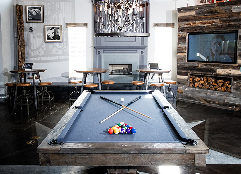 A pool table in a room with a fireplace and a television.