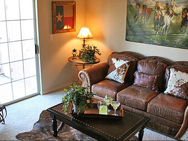 A living room with a brown couch, a table with a tray on it, and a painting on the wall.
