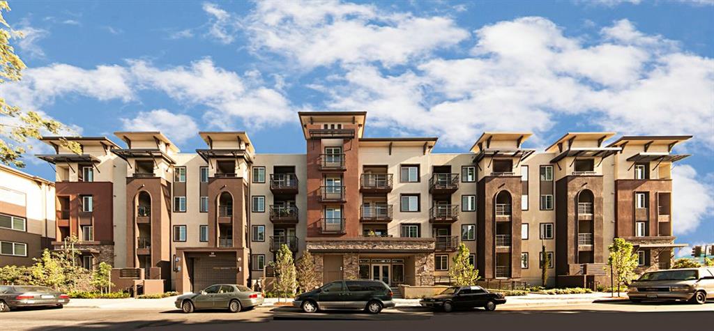 A large, modern apartment complex with multiple balconies and a central courtyard.